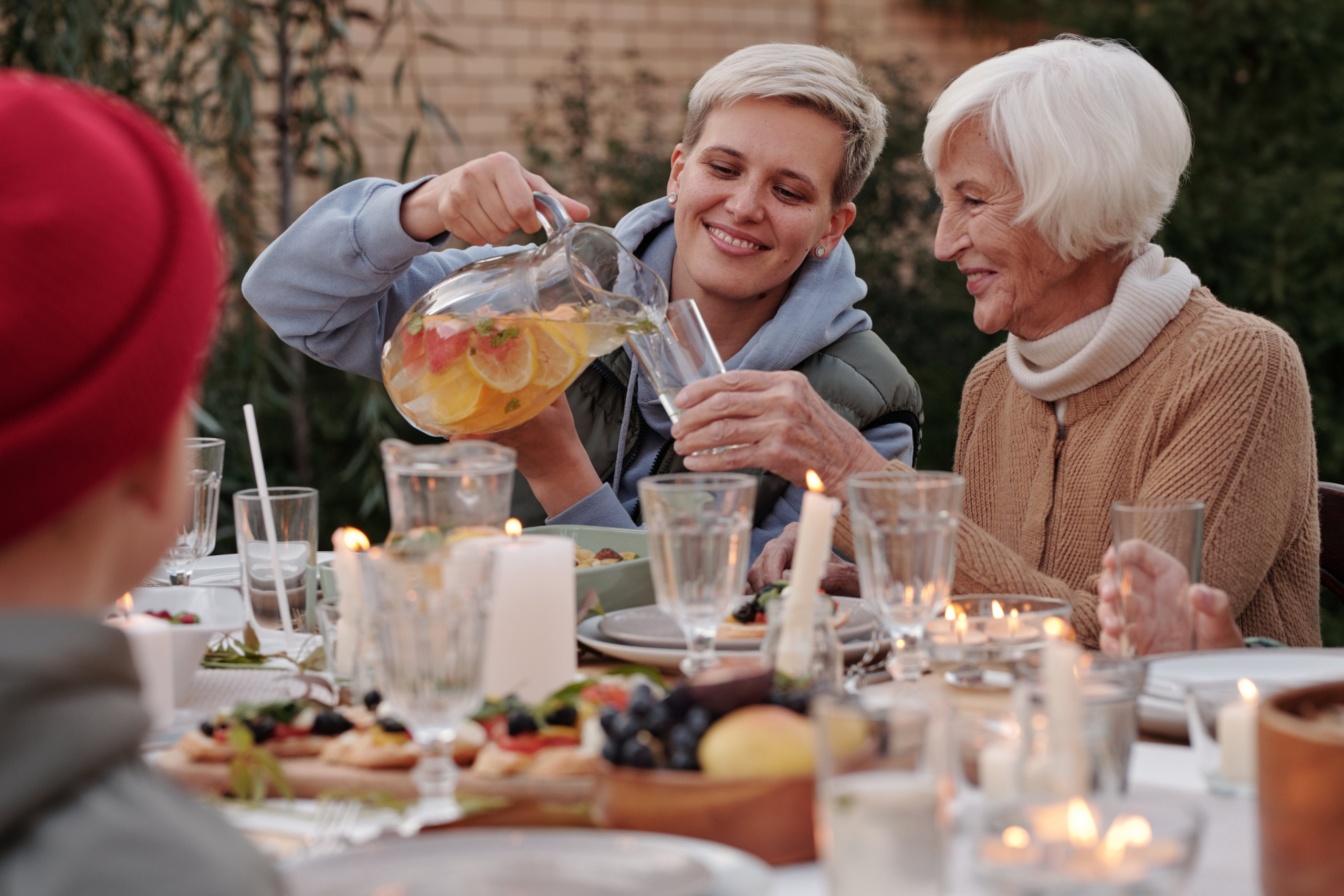A woman pours iced tea for an older woman at a dinner table. How Gratitude in Relationships Boosts Joy